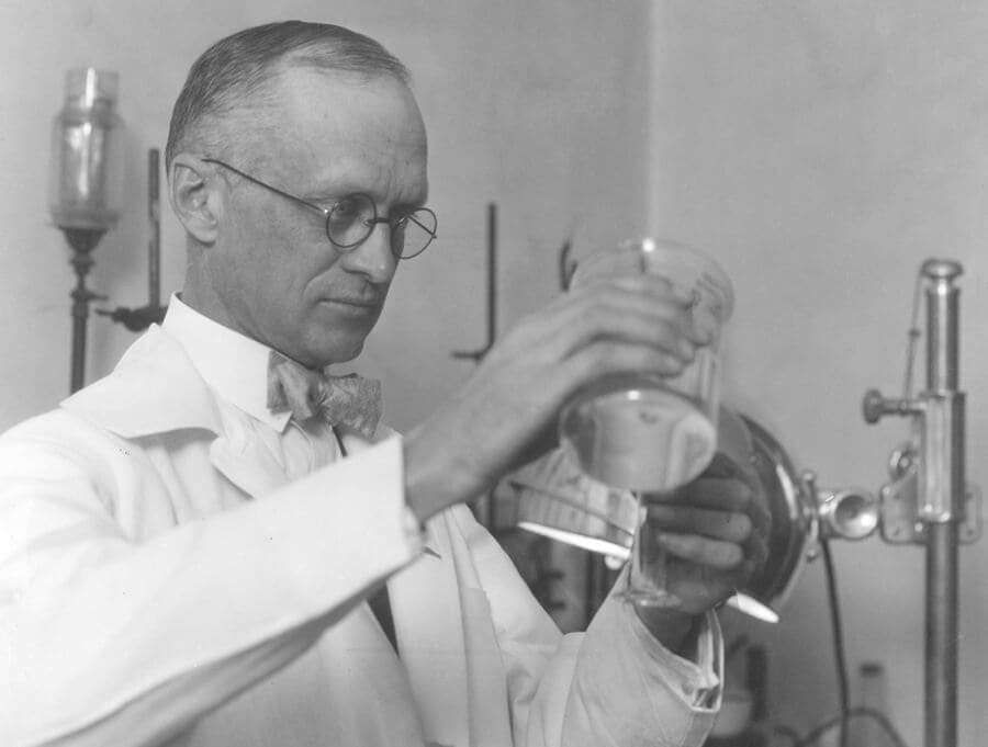 Black and white image of Professor Harry Steenbock pouring a solution in a laboratory