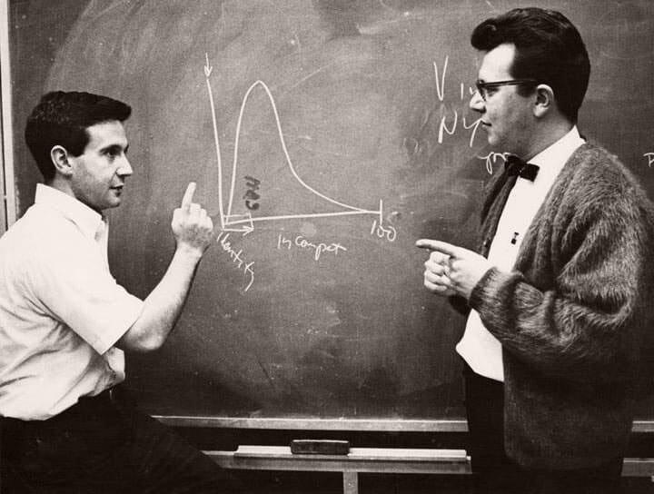 Black and white image of two academics working at a chalkboard.