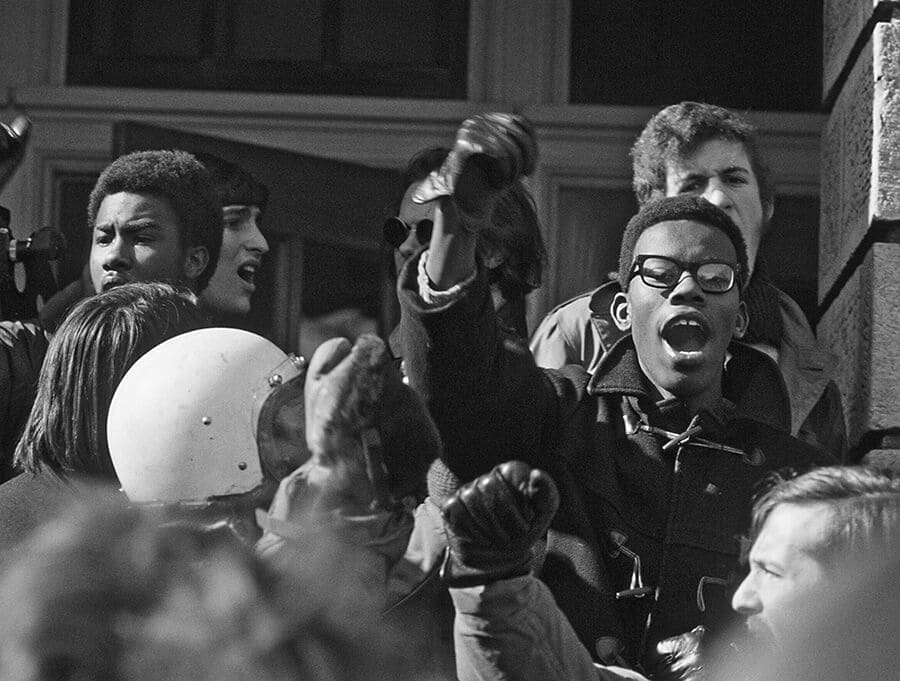 Student participant in Black Student Strike with raised fist. Other students visible behind him.