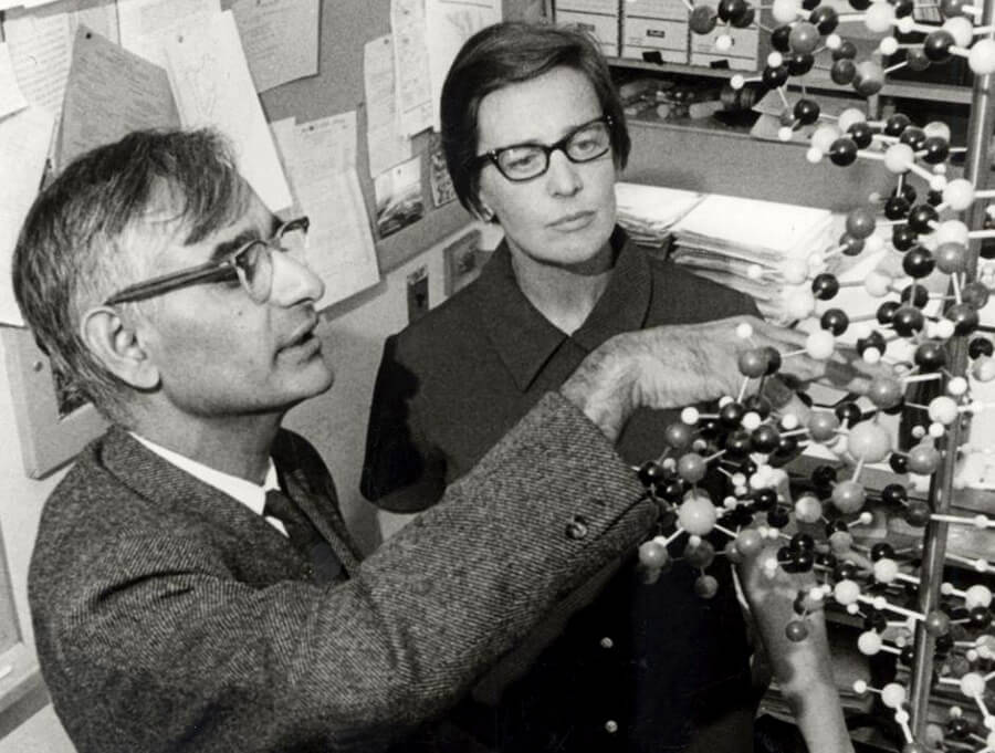 Black and white image of Har Gobind Khorana and a woman examining a gene structure in a lab.
