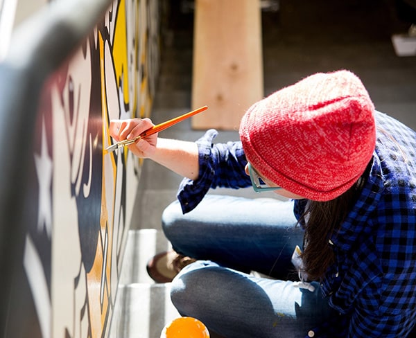 Person cleaning the Watrous Mural with a paintbrush at the UW–Madison Chazen Museum of Art