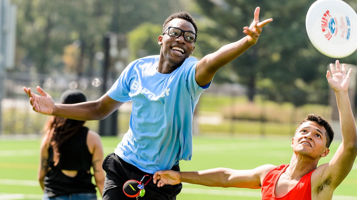 Two students reach for a flying disc during a game of Ultimate