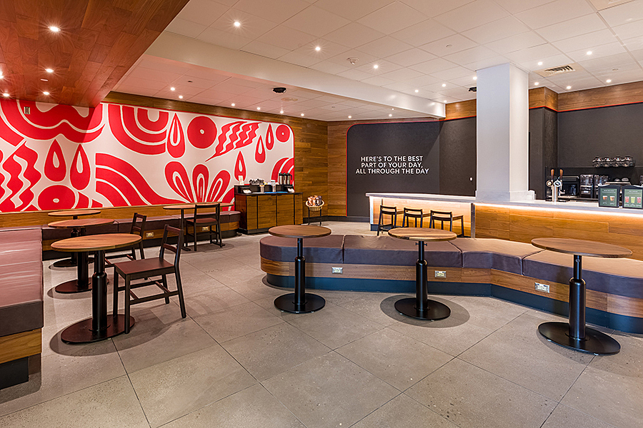 Round tables in open seating area with red and white decorative art on wall.