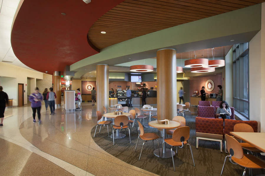 Open seating area with coffee station and people walking in background.