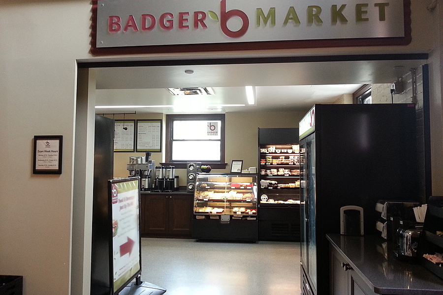 Badger Market sign fixed above entryway with self-serve stations in background. 