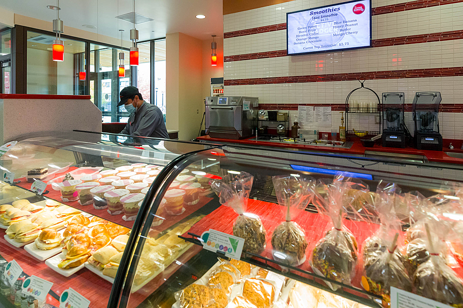 Candy apples, baked goods, sandwiches and other food within glass display. 