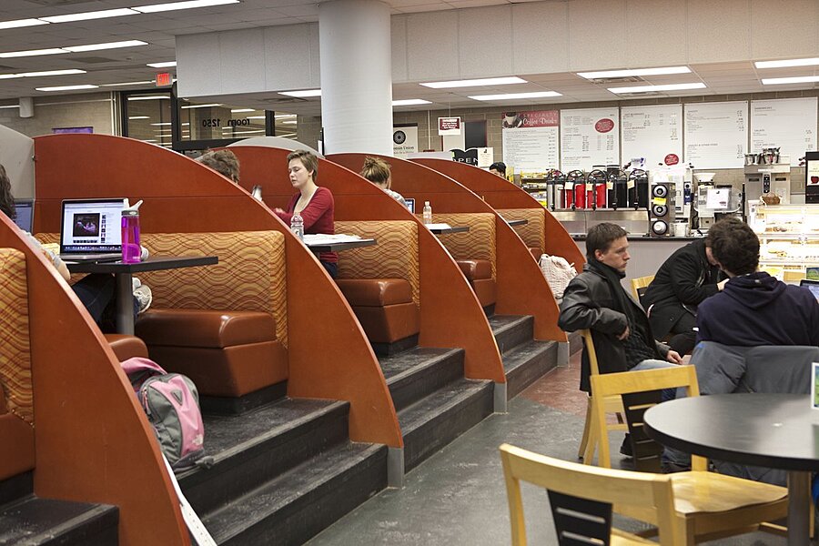 Students sitting at the tables and booths in cafe.