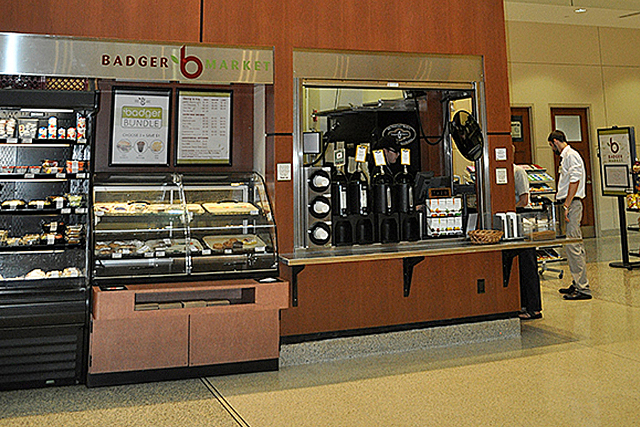 Badger Market sign positioned above self-serve food and beverage stand.