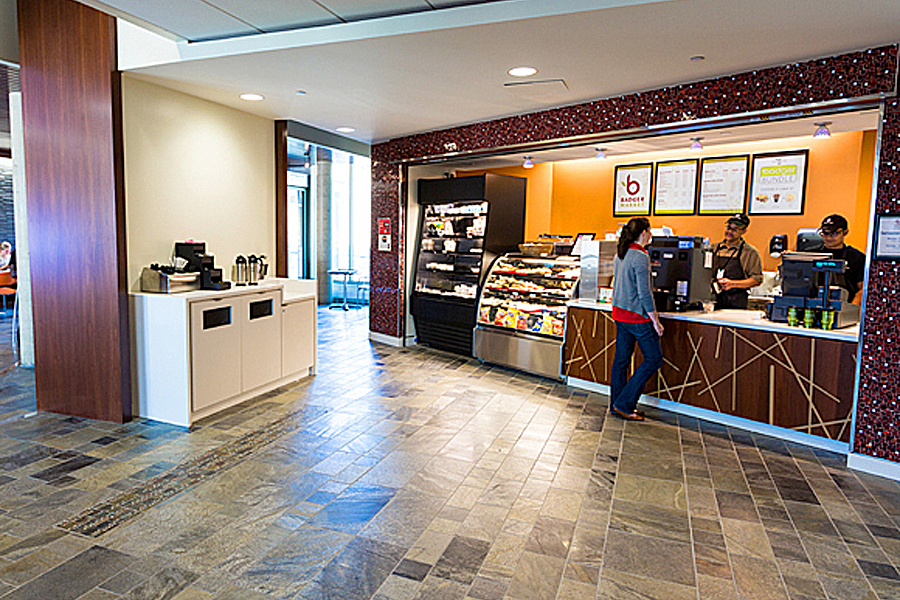 Two staff members standing behind sales counter while person places order. 