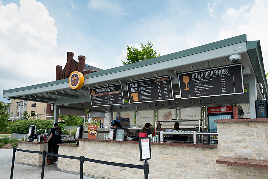 Outdoor food and beverage stand with menus fixed to awning and stanchion in foreground.