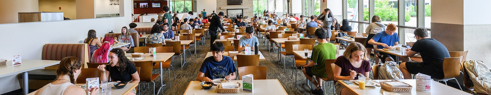Students eating lunch in a brightly lit dining hall.