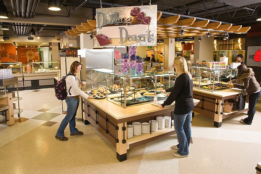 People positioned around two dining stations at Rheta's Market.