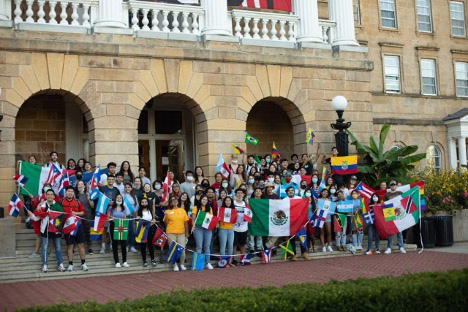 Students in front of Bascom Hall holding colorful flags representing their identities and culture.