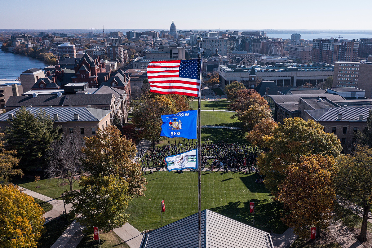 Aerial photograph of three flags flying atop Bascom Hall: the American flag, the Wisconsin State flag, and the flag of the Ho-Chunk Nation.