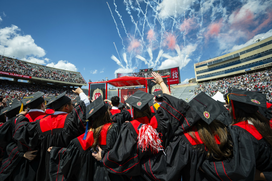 Graduates celebrate at Camp Randall as fireworks launch in the sky above Camp Randall Stadium.