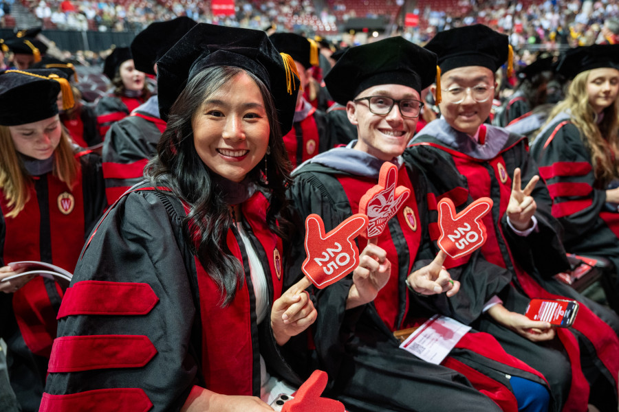 People in commencement robes smiles and clap.