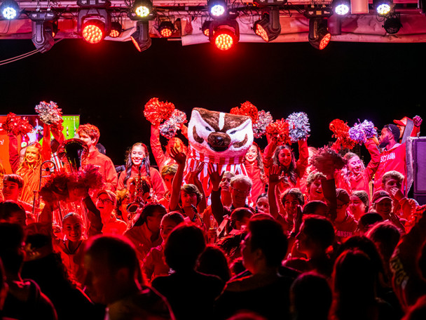 A crowd in red light cheers as Bucky Badger and UW-Madison’s spirit squad take the outdoor stage at the Memorial Union Terrace.