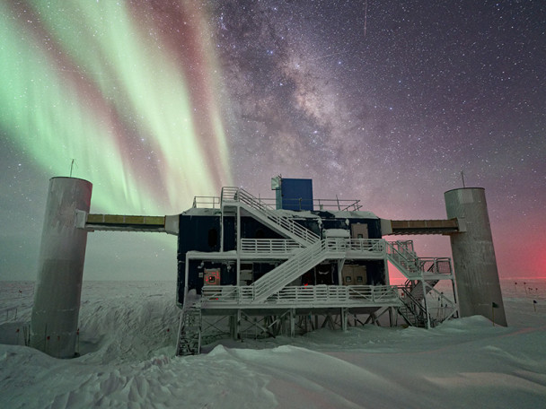 The IceCube Laboratory with auroras and the Milky Way in the background.