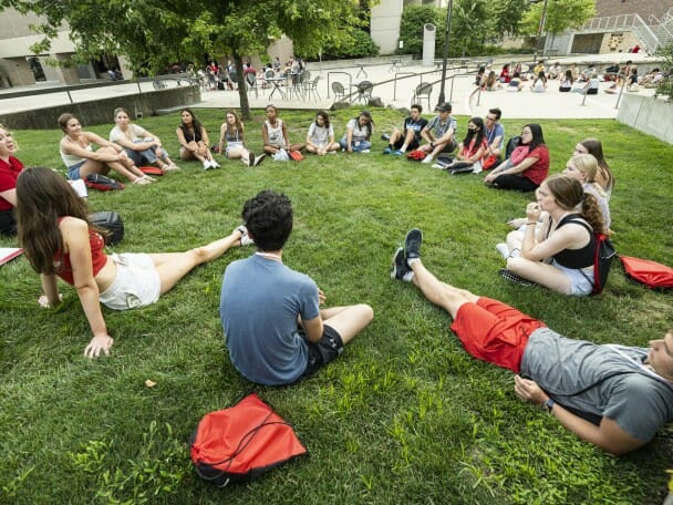 Students sit in a circle in the grass