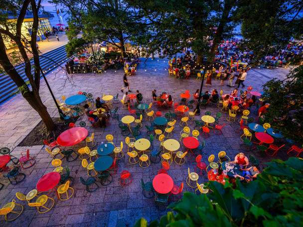 Colorful tables and sunburst chairs dot the Memorial Union Terrace at dusk on a summer evening