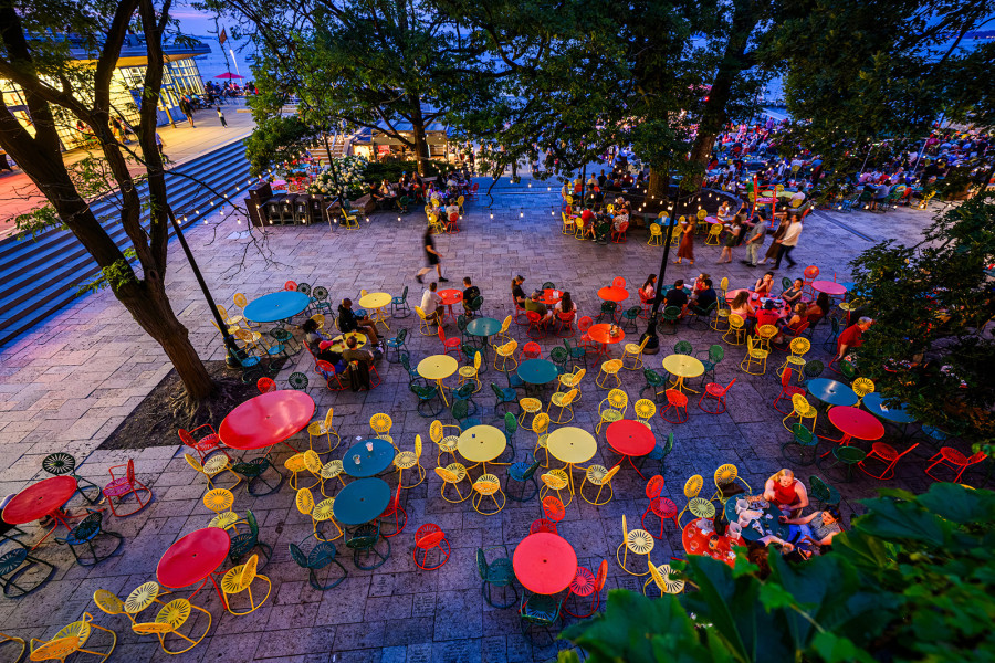 Colorful tables and sunburst chairs dot the Memorial Union Terrace at dusk on a summer evening