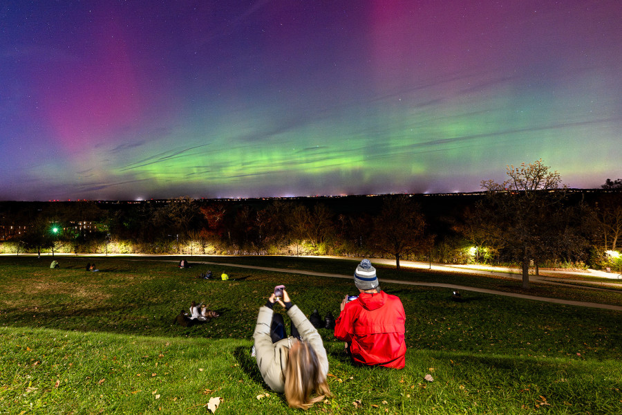 People sit on Observatory Hill watching the Northern Lights over Lake Mendota