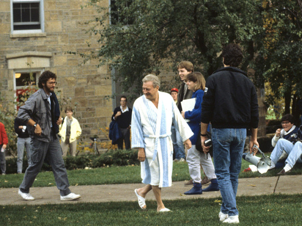 A group of people gathered outdoors on Bascon Hill, with Rodney Dangerfield (as character Thornton Melon) in a bathrobe and slippers among casually dressed students and actors.