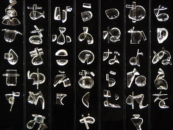 The glass artwork, Iroha, is displayed in front of a black backdrop.