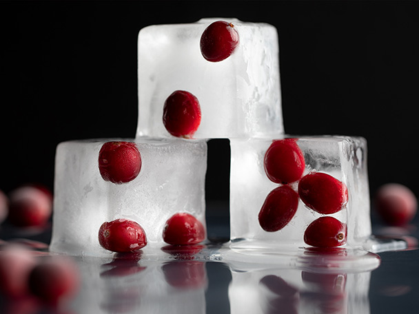 A pyramid of three ice cubes, each with frozen cranberries inside of them.