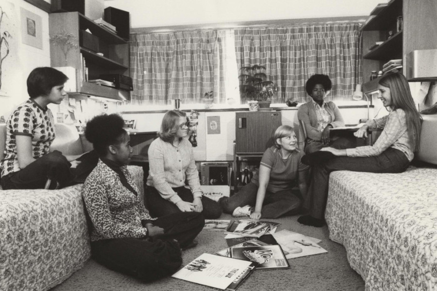 A black and white photo of female students in a dorm room listening to music in the 1960s.