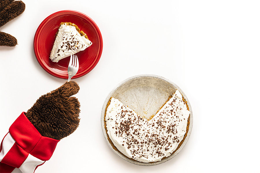 Bucky Badger’s paws are shown digging into a piece of fudge bottom pie on a red plate with a fork.