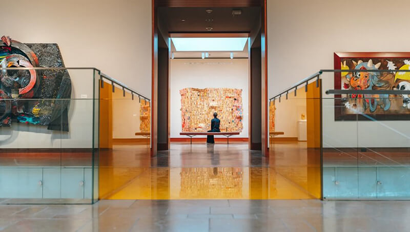 A patron sits on a bench studying a work of art on the wall inside the Chazen Museum of Art.