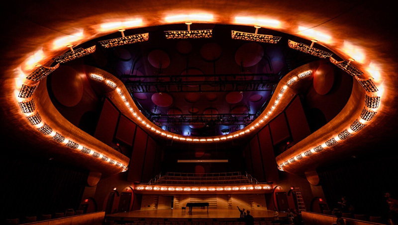 The theater lights glow in a ring underneath the Mead Witter Foundation Concert Hall’s balcony.