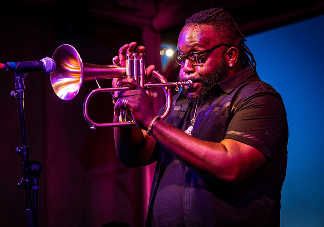 A musician plays a flugelhorn during a live performance