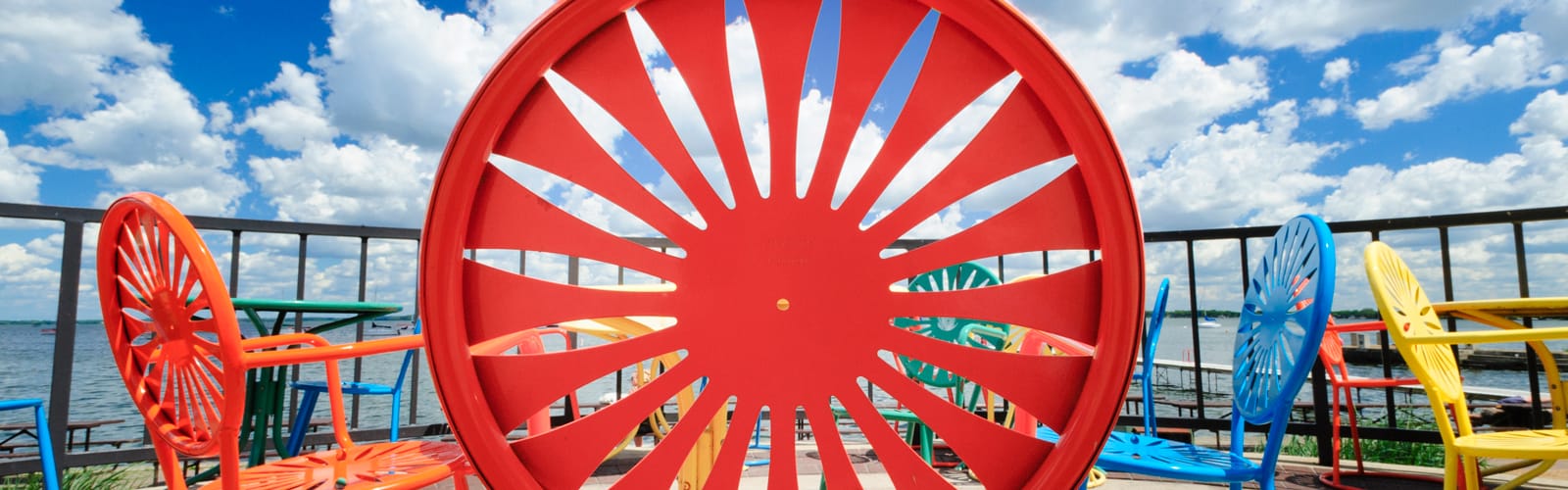 Brighly colored Union Terrace chairs lined up in front of Lake Mendota