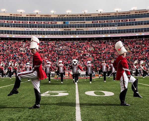 A UW drum major high steps across the Camp Randall football field